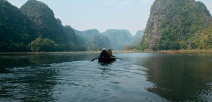 A longboat paddling through karst landscape in Ninh Binh in Vietnam