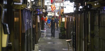 A man walks in a side street contemplating a number of different izakaya establishments in Shibuya, Tokyo