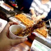 Skewer of South Korean street food being dipped into cup of sauce