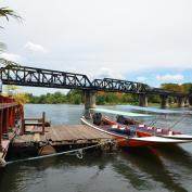 Boats at jetty in front of bridge over River Kwai