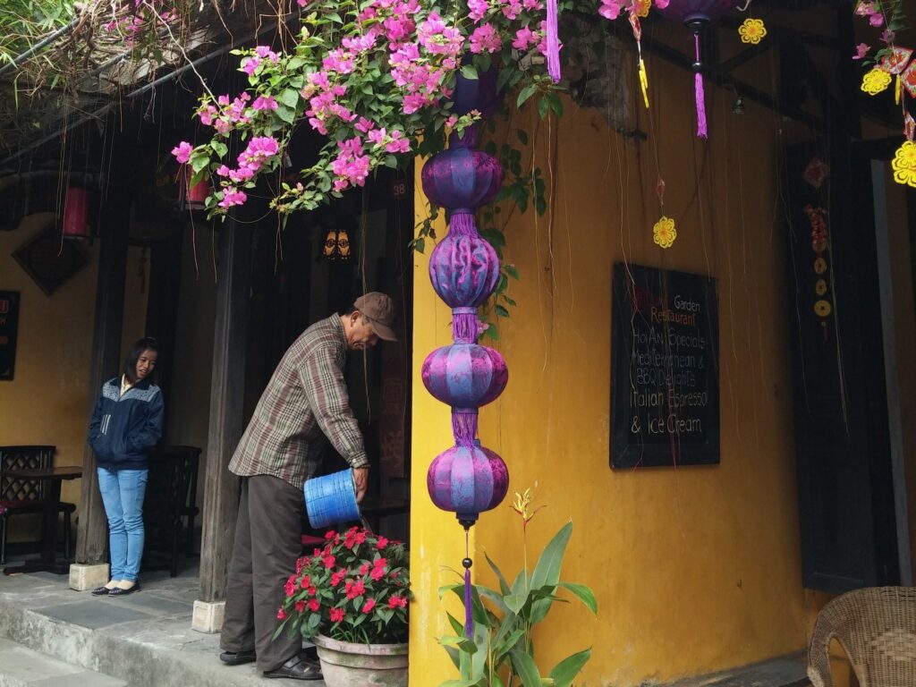 Vietnamese man watering colourful flowers