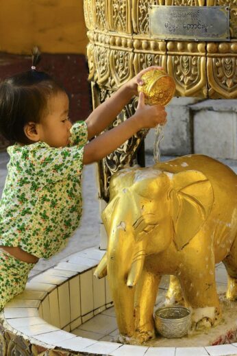 Burmese girl washes elephant statue