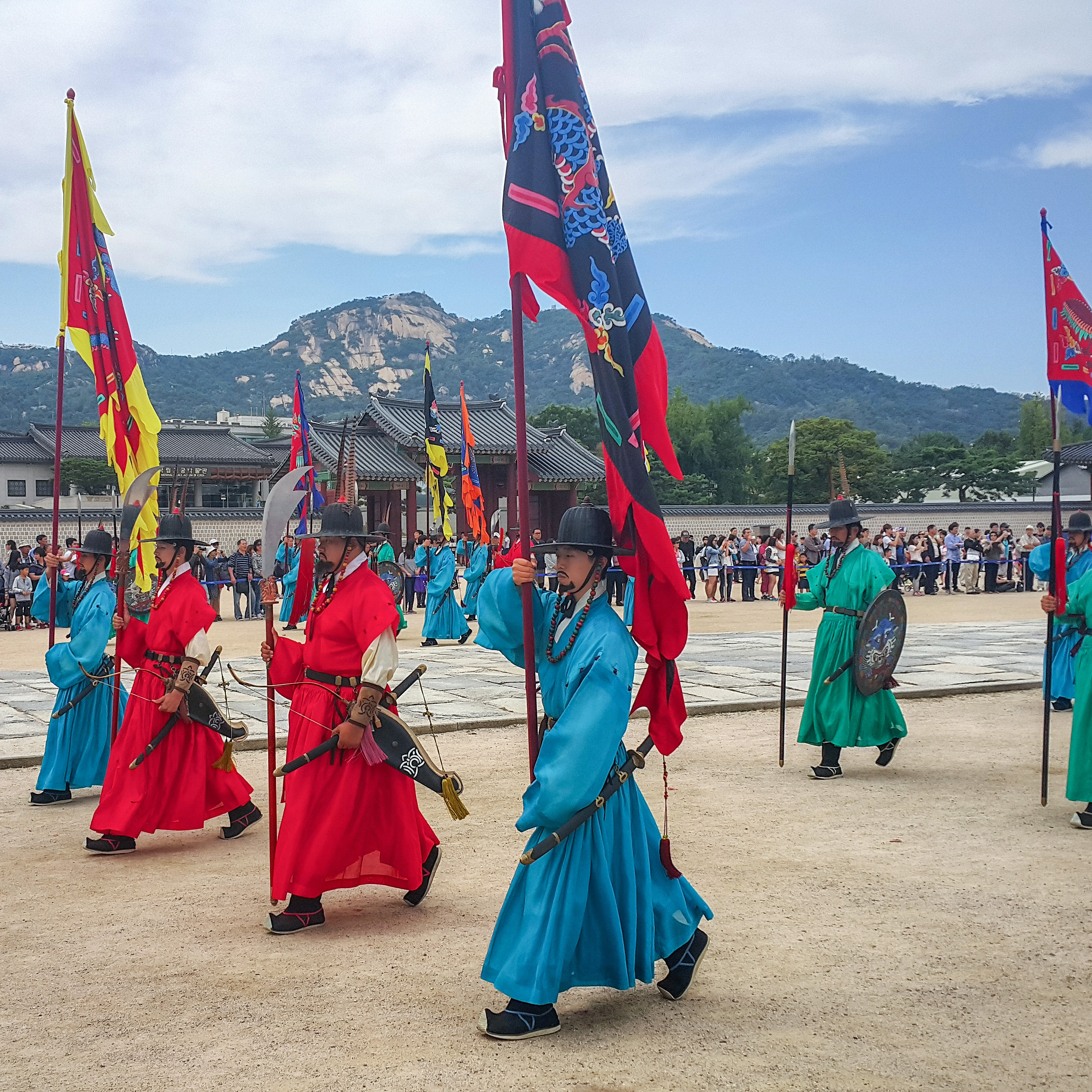 Procession of guards in brightly coloured traditional costume carrying flags