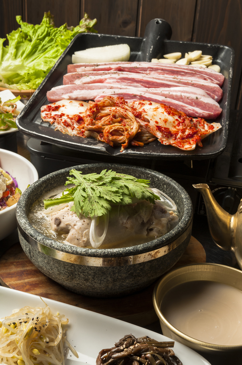 Meats cooking on grill with side of kimchi
