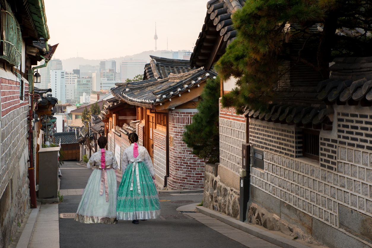Two ladies wearing traditional Korean dress walking down street in Seoul