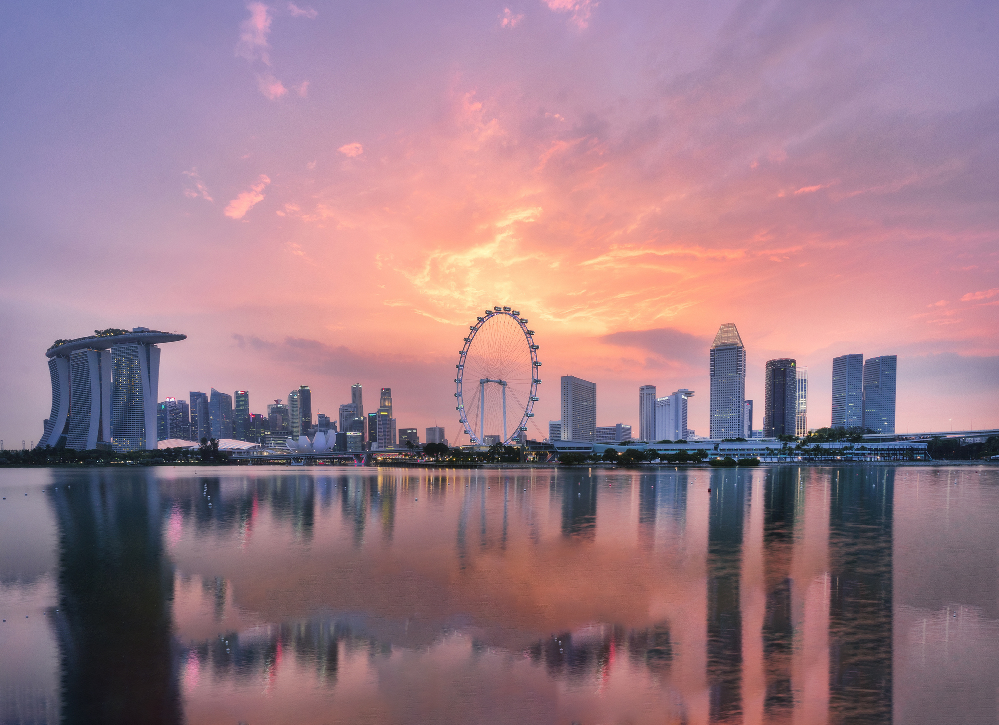 Singapore Skyline sunset_iStock-1181647284_P. Kijsanayothintttt.jpg Warm and pink sky tones bath Singapore's skyline at sunset , with reflections on the water