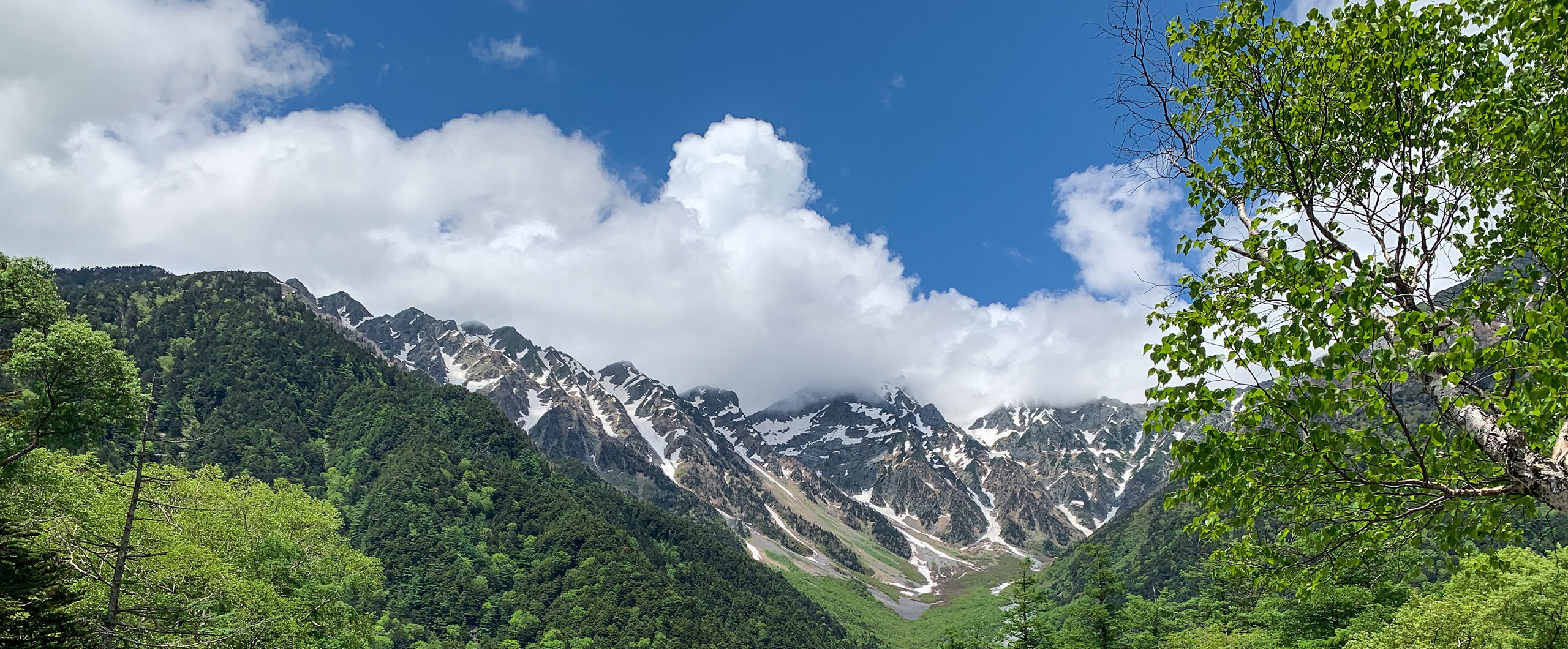 kamikochi-in-early-summer-hero Snow-capped mountains are surrounded by beautiful forest in the valley of Kamikochi, central Japanese alps