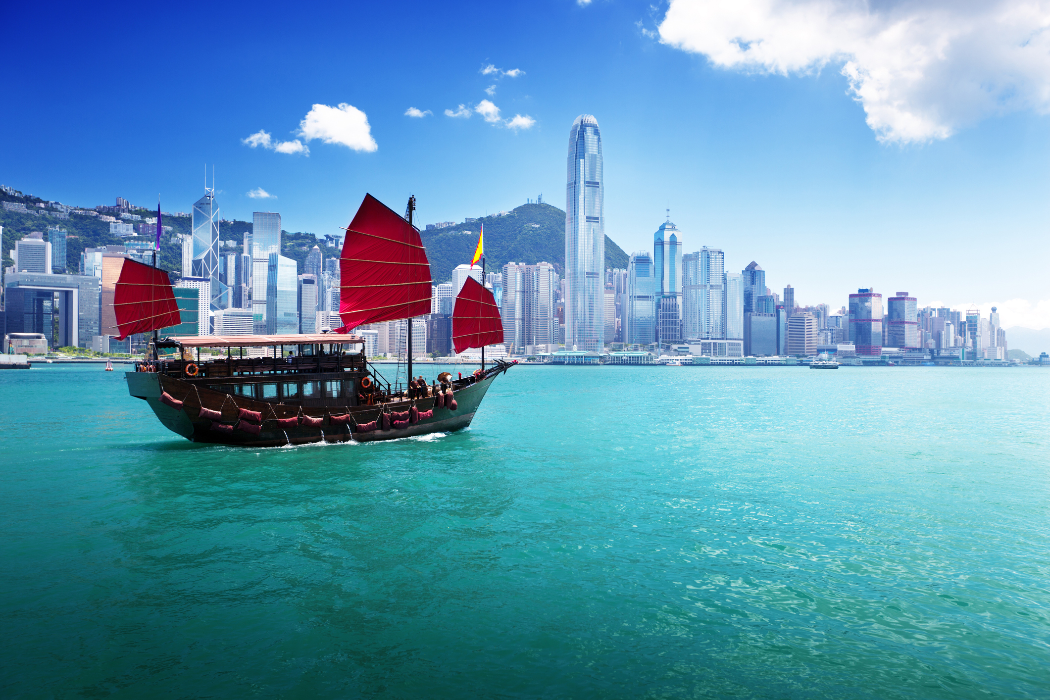 Junk boat with red flags crossing Hong Kong harbour