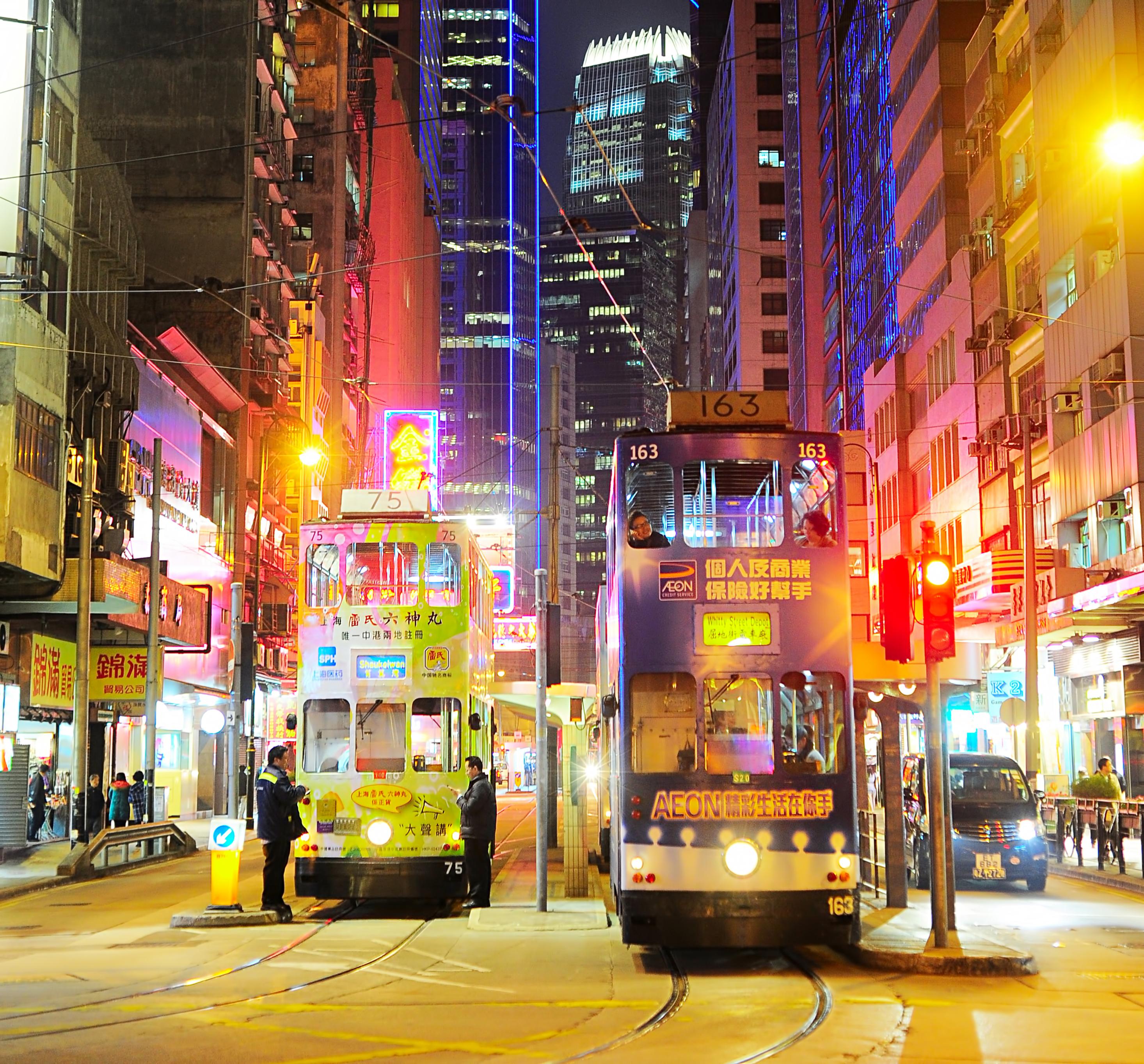Trams at night lit up by neon signs
