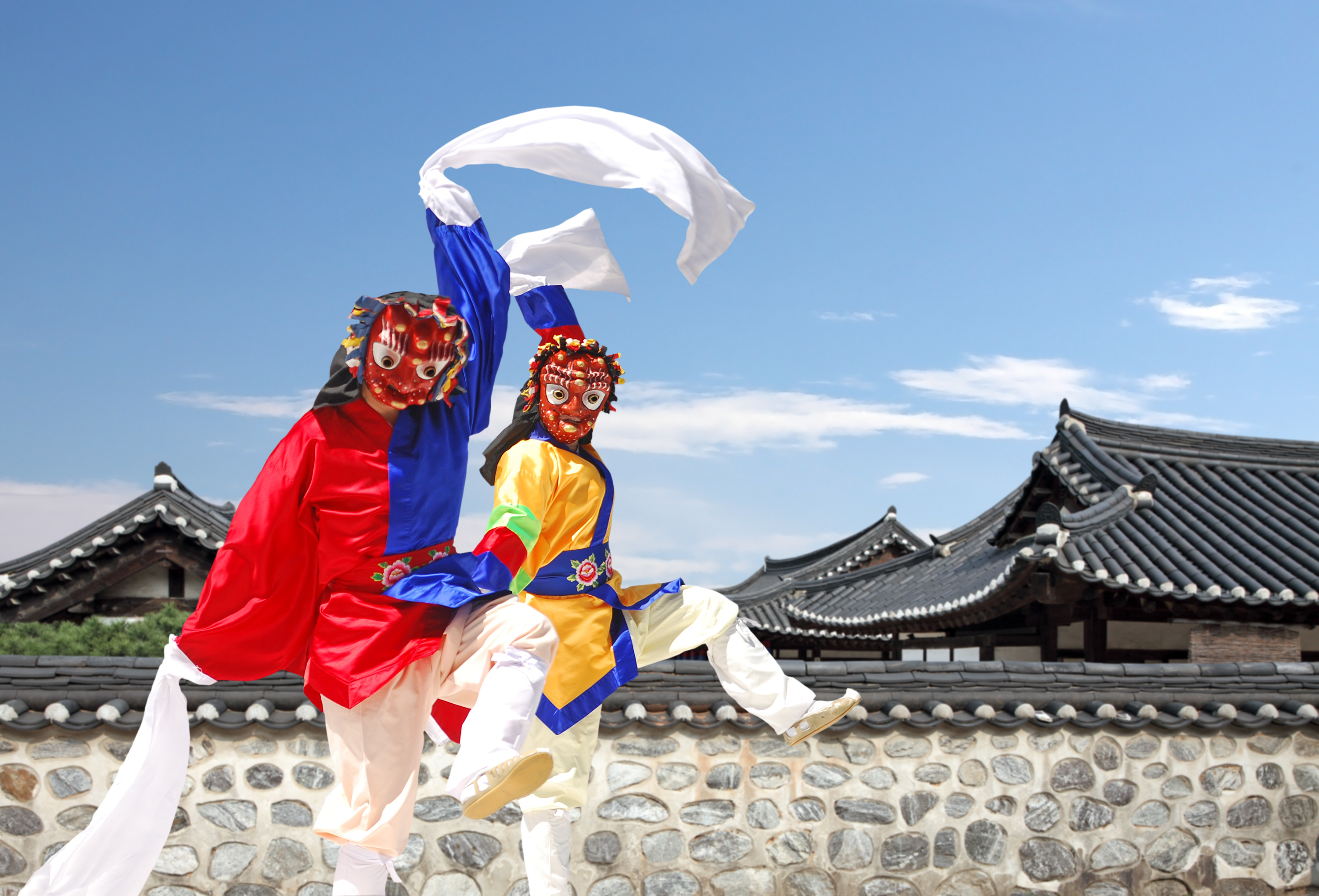 SKFA HERO South Korea Family Adventure dancers Two traditional folk dancers wearing masks dance in front of hanok houses in South Korea