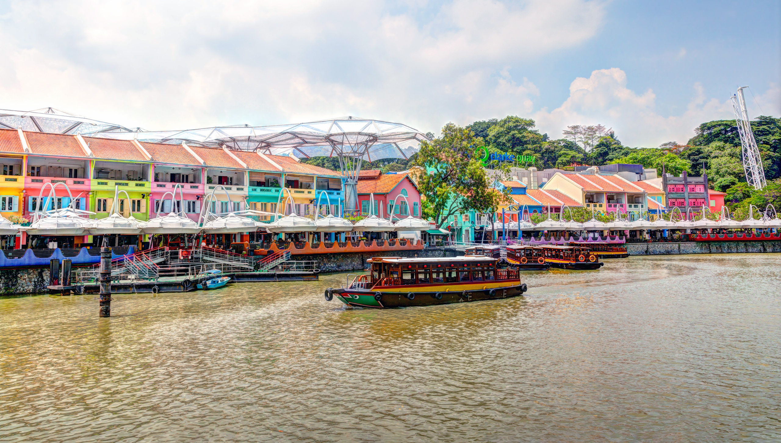 Overview page Hero - Singapore Colorful buildings stand out next to a passenger boat in Singapore's Clark Quay