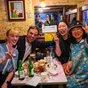 A group of people posing with peace signs at a table filled with food and drinks