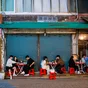 Local South Koreans enjoying food whilst sitting outside on red stools in a street restaurant