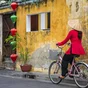 Vietnamese woman riding a bicycle, old town in Hoi An city, Vietnam