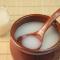 Creamy white Makgeolli rice wine in brown cup with spoon