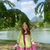 A woman standing in front of a lake with a lime green top and magenta skirt