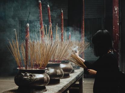 A woman lights incense at a shrine