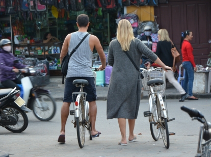 Couple pushing bicycles across busy road in Vietnam