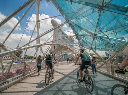 Cycling across modern bridge by Marina Bay, Singapore 