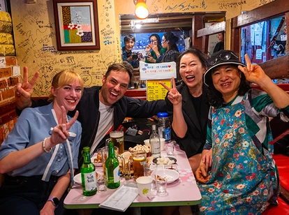 A group of people posing with peace signs at a table filled with food and drinks