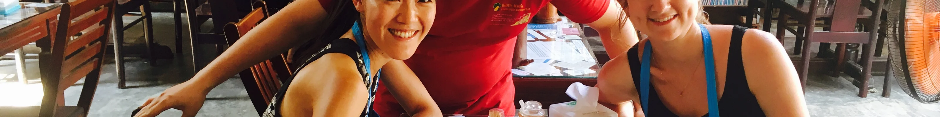 Two friends smiling with a waiter in Vietnamese restaurant 