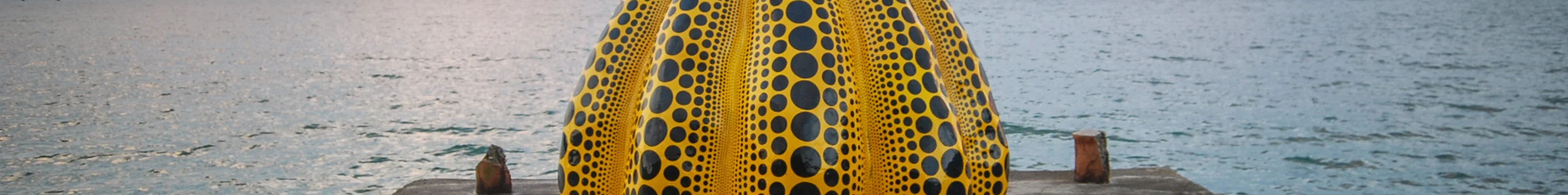 Yellow and black pumpkin sculpture on pier at Naoshima Island 