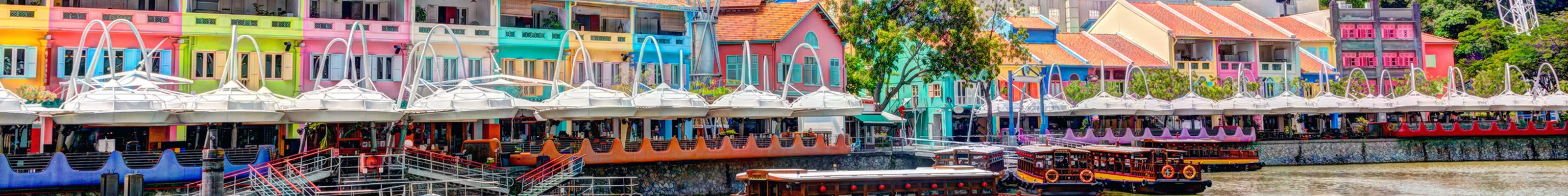 Colorful buildings stand out next to a passenger boat in Singapore's Clark Quay