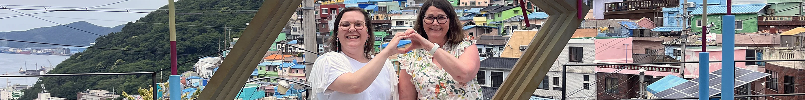 Two friends pose together in front of Gamcheong Village in Busan, South Korea
