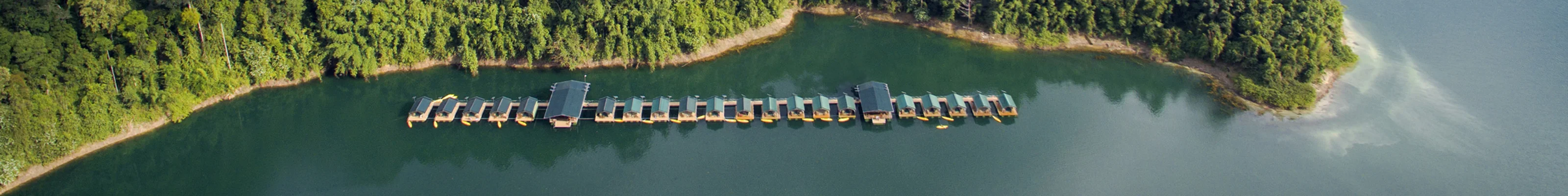 Overwater bungalows next to lush outcrop of land in Khao Sok National Park