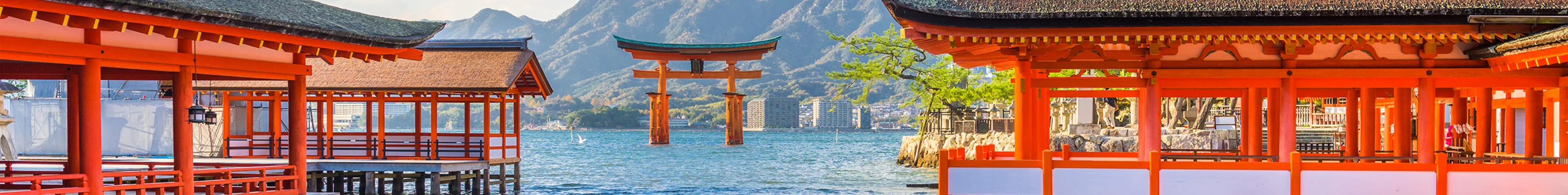 View across the water towards Miyajima's red floating torii gate, with Itsukushima shrine visible in the foreground