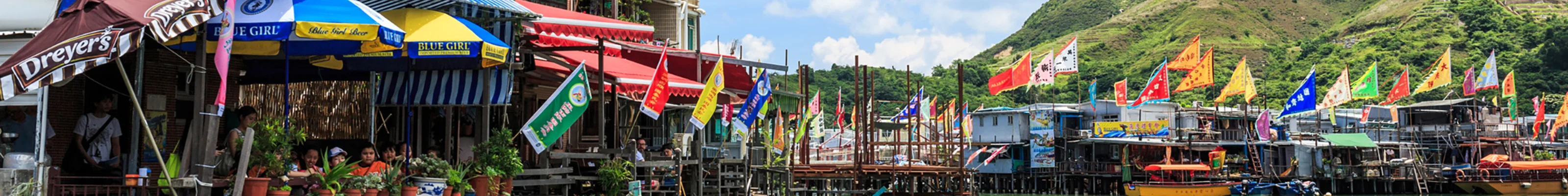 Fishing boats docked up by covered jetties alongside colorful houses in Tai O Village in Hong Kong's Lantau Island