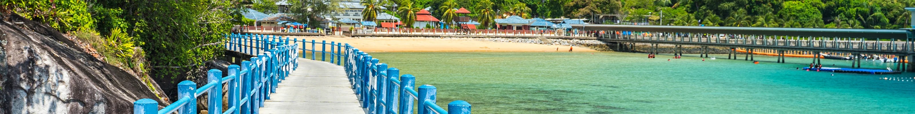 Concrete walkway with blue handrails along Tioman island's beautiful jungle backdrop
