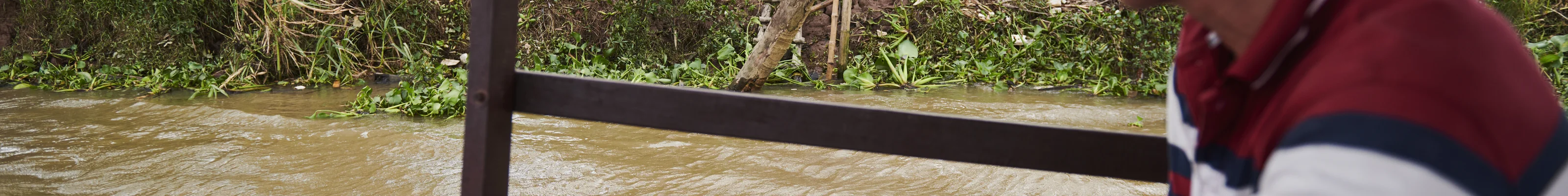 A local Vietnamese boat driver on the Mekong Delta being waved to by women in the jungle on a boat cruise