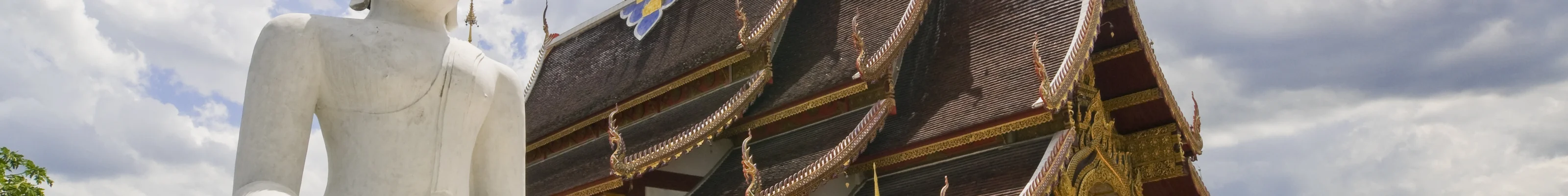 White buddha statue next to traditional golden temple in Chiang Mai