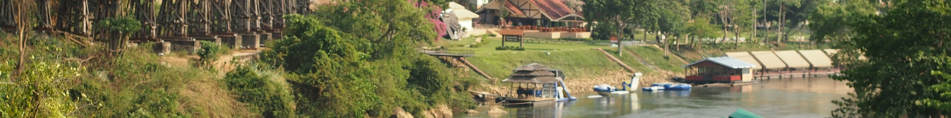View of KANCHANABURI river bend and abandoned railway with buildings and boats 