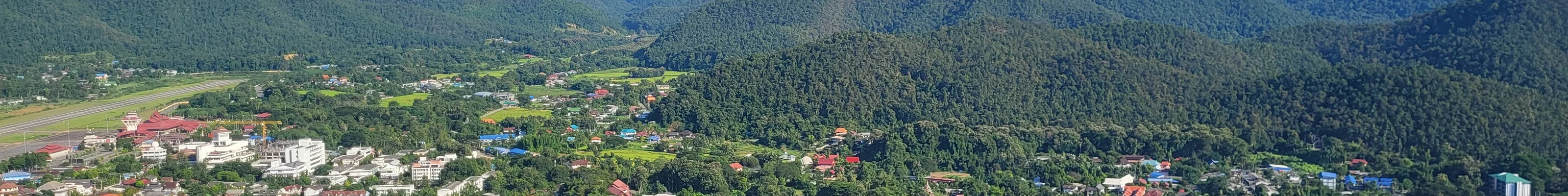 Elevated view of a town situated between green mountains