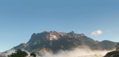 Morning light on the dramatic snowed peak of Mount Kinabalu, surrounded by lush jungle