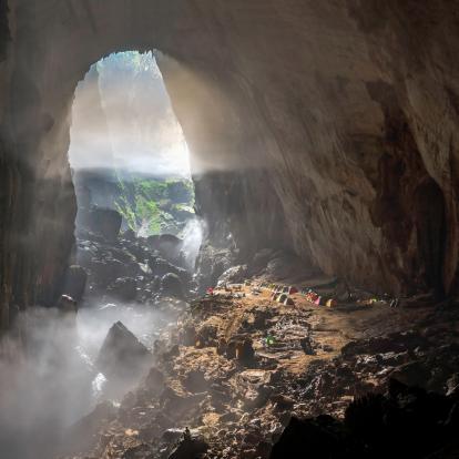 Mist gently covers individual tents lined up in massive cave entrance in Son Doong, Phong Nha