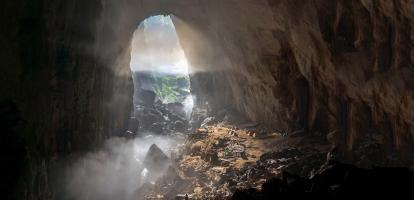 Mist gently covers individual tents lined up in massive cave entrance in Son Doong, Phong Nha