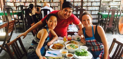 Two friends smiling with a waiter in Vietnamese restaurant