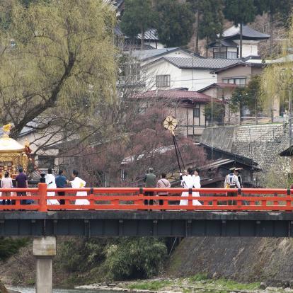 Procession of people in traditional garb over bridge in the centre of Takayama