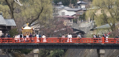 Procession of people in traditional garb over bridge in the centre of Takayama