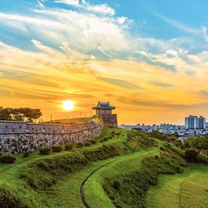 Suwon fortress walls at sunset with city skyline in background