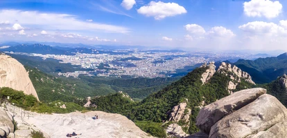 People sitting on rock in Bukhansan National Park overlooking city
