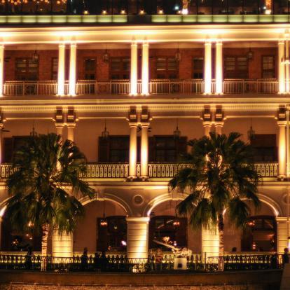 Heritage building lit up at night with palm trees outside