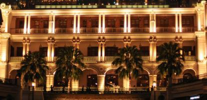 Heritage building lit up at night with palm trees outside