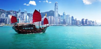 Junk boat with red flags crossing Hong Kong harbour