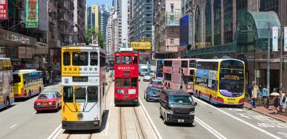 Trams and buses running alongside each other on street in Hong Kong