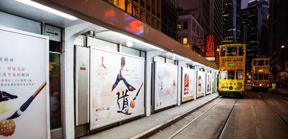 Yellow tram travelling along tracks alongside advertisements at night