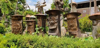 Jangseung totem poles lined up among bushes in Andong Folk Village in South Korea